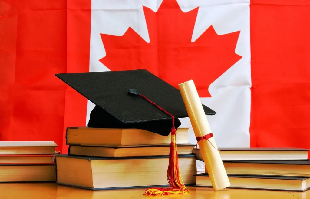 Birrete de graduación y diploma sobre libros con la bandera de Canadá de fondo, representando la convalidación del año escolar en Canadá.