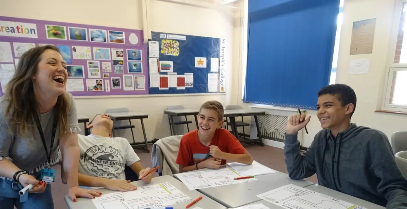 Profesora y alumnos adolescentes sonriendo en clase durante un curso de inglés en el extranjero para jóvenes