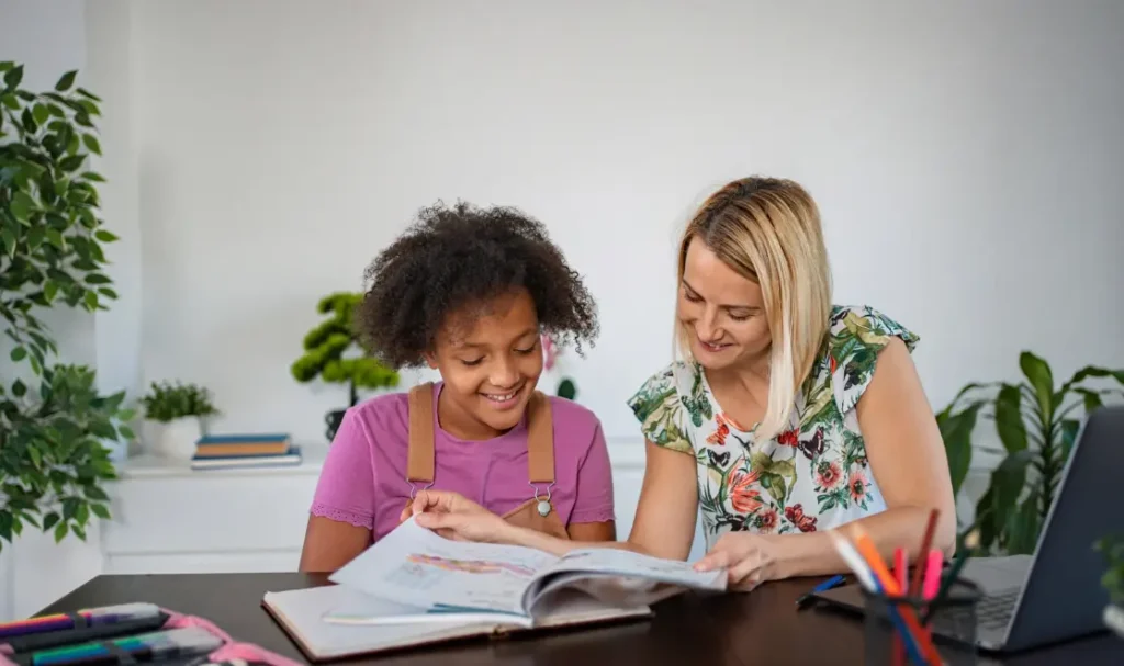 Profesora particular dando una clase individual a una alumna joven durante un curso de inglés en casa del profesor.